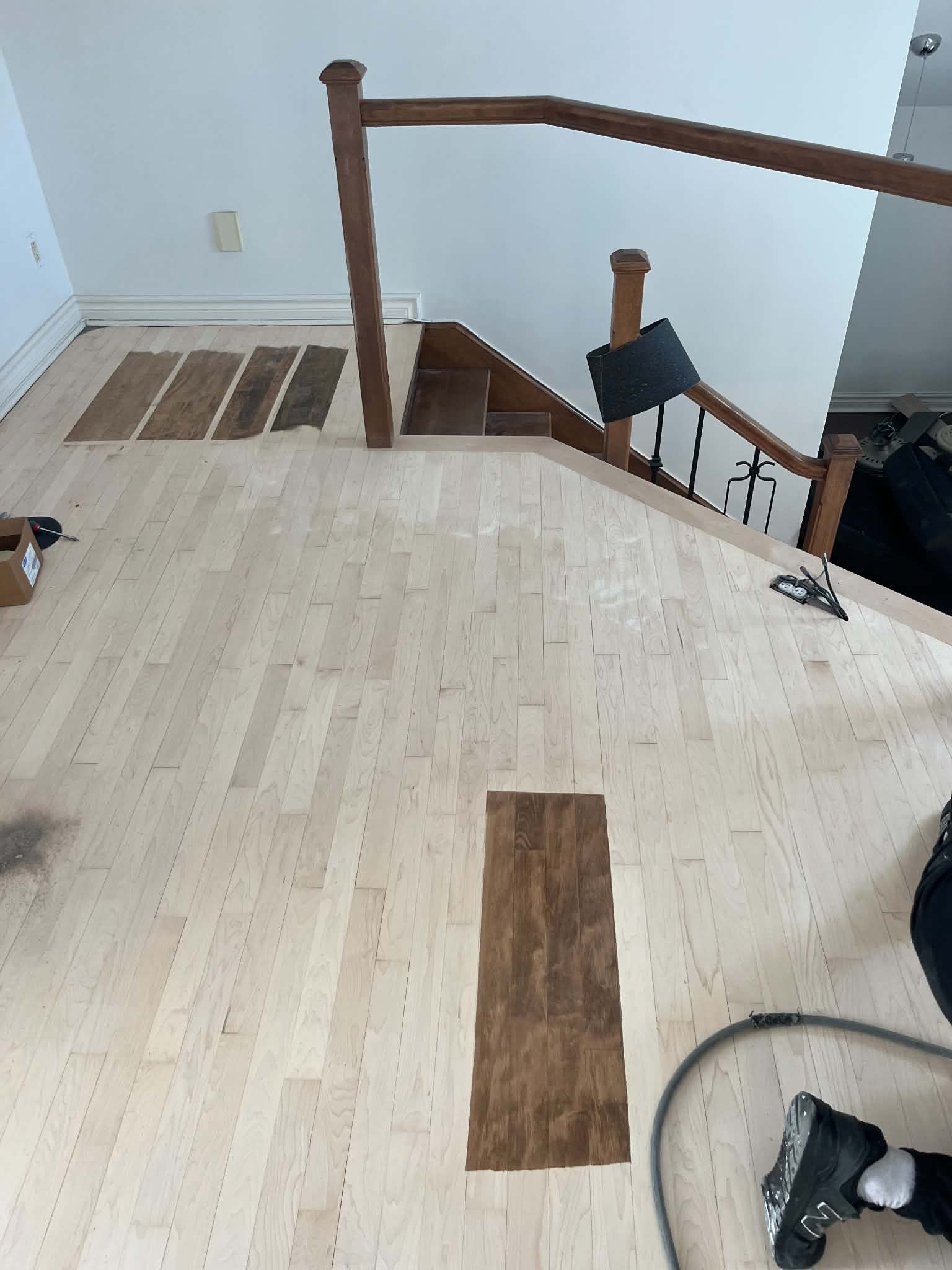 Stain samples on a freshly sanded floor at the top of a staircase